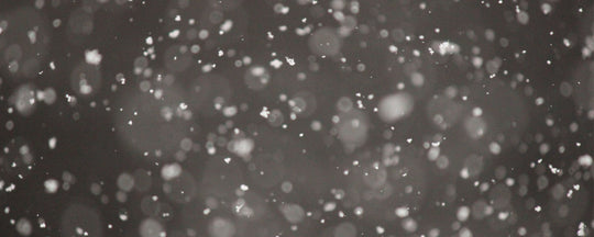 A serene image of gently falling snow against a muted gray background, evoking the quiet and chilly ambiance of winter.