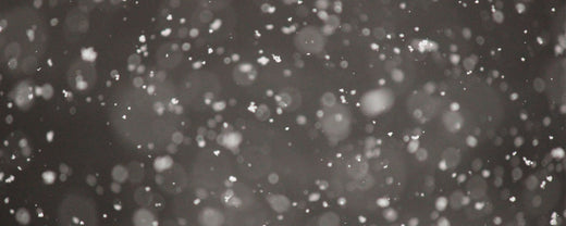 A serene image of gently falling snow against a muted gray background, evoking the quiet and chilly ambiance of winter.