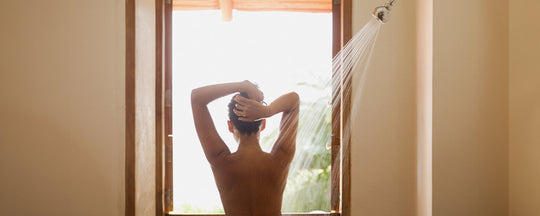 A woman enjoying a refreshing shower, with water cascading over her, symbolizing the daily ritual of cleansing and self-care.