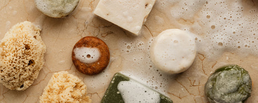 Assortment of handmade, eco-friendly soaps in various colors and textures, some with visible natural ingredients like herbs and oatmeal, representing sustainable skincare options.