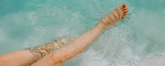 Woman's legs dangling in a swimming pool, capturing the essence of summer relaxation.