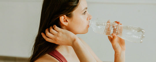 Girl hydrating with a glass of water, emphasizing the importance of internal hydration for maintaining healthy, moisturized skin during winter.