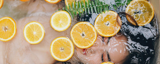 A serene woman relaxing in a bathtub, with slices of fresh orange placed on her eyes, symbolizing a luxurious and natural skincare routine.