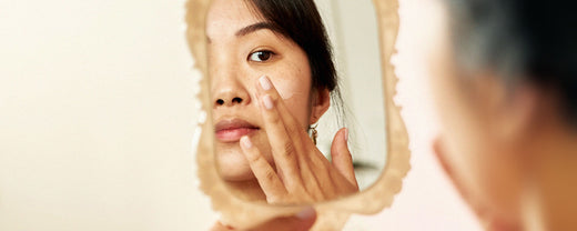 Thoughtful woman examining her skin in the mirror, reflecting on her weekly skincare ritual