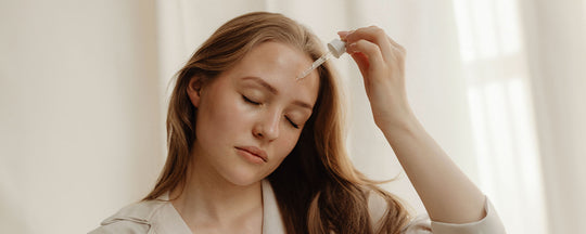 Woman applying facial serum, demonstrating a step in her skincare routine.