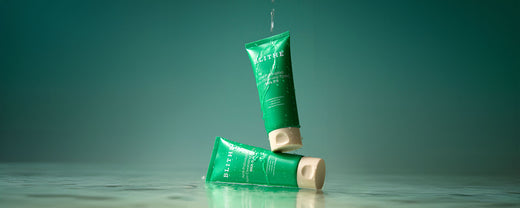 Two tubes of Blithe Anti-Polluaging Pore Cleansing Foam BHA 0.5% against a green background, highlighting its effectiveness for oily and acne-prone skin, with salicylic acid for deep cleansing and sebum control.
