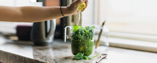 Fresh spinach in a measuring cup being squeezed with lemon juice, symbolizing the importance of a nutrient-rich diet for healthy skin.