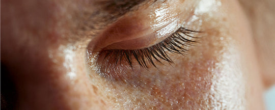 Close-up of a person's closed eye with moisturized, glowing skin.