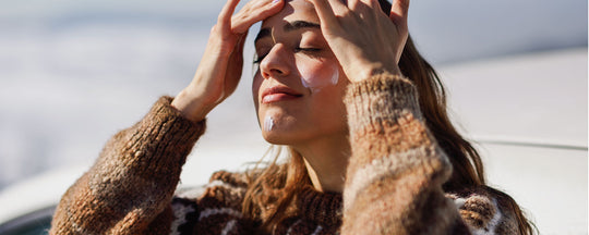 A cheerful woman applying sunscreen, capturing the essence of a proactive and joyful approach to winter skincare protection.