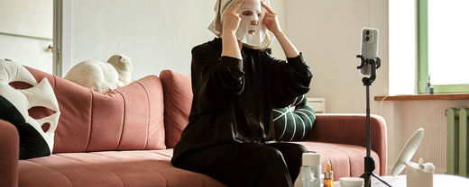 Urban skincare routine: Woman applying a face mask while live-streaming, addressing pollution and sebum control, essential for combating urban skin issues.