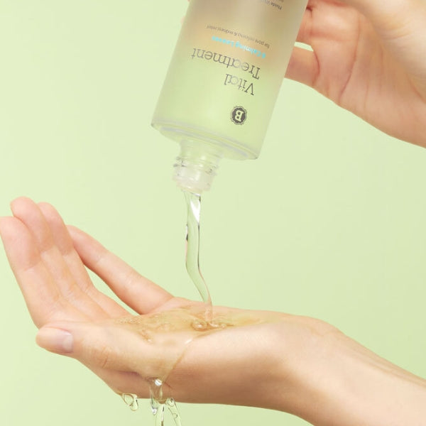 Vital Treatment liquid pouring on hand against a green background