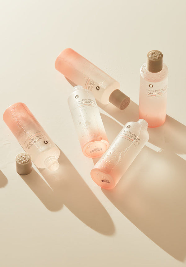 five bottles of Blithe Cosmetics’ cleansing water laying on a beige surface