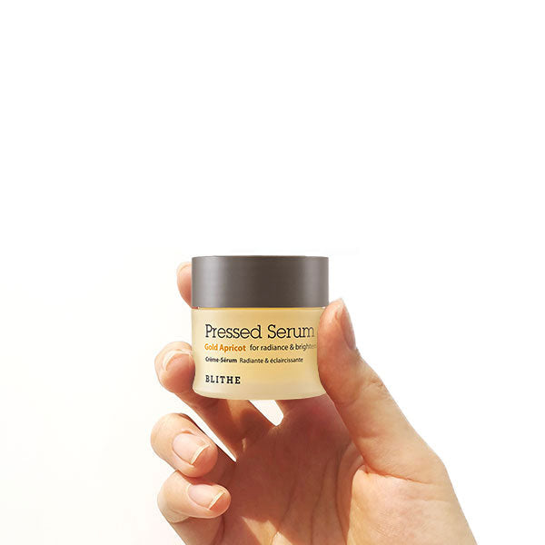 a hand holding a container of Apricot Pressed Serum