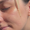 Application of Blithe Targeted Blemish Serum with Niacinamide 5.0 on a woman's cheek, demonstrating serum texture and skin interaction.
